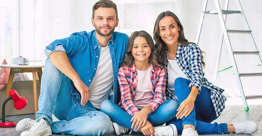 Mamá, papá e hija latinos sonriendo aprendiendo de presupuesto personal