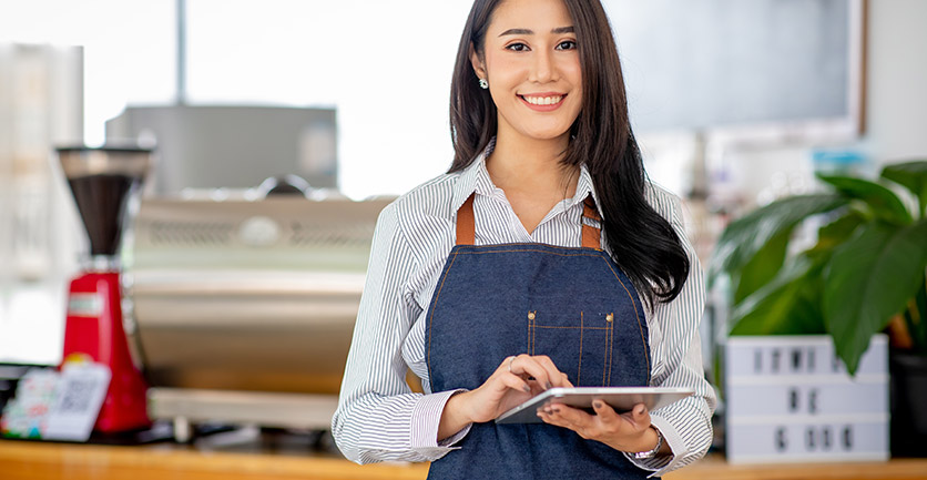 Empresaria latina sonriente con ipad en su mano aprendiendo a hacer pagos a terceros