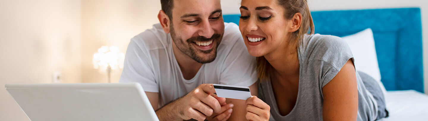 Esposos sonrientes mirando juntos tarjeta de crédito amparada