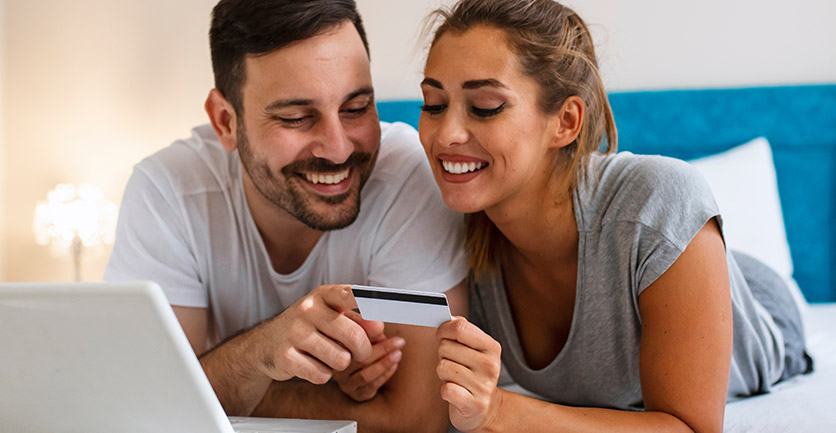 Esposos sonrientes mirando juntos tarjeta de crédito amparada